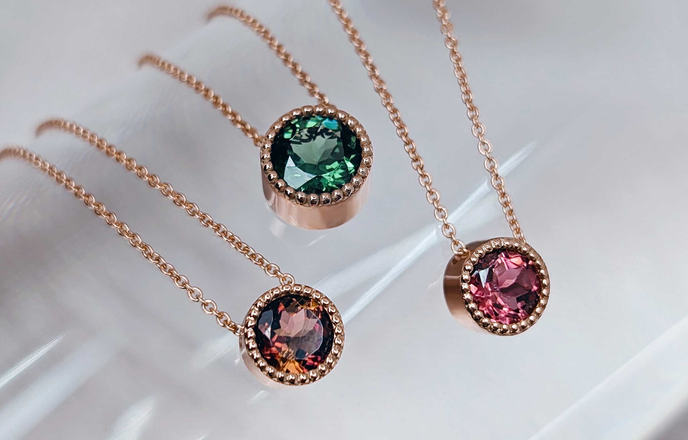 Green, pink and bicolour tourmaline milgrain necklaces in rose gold