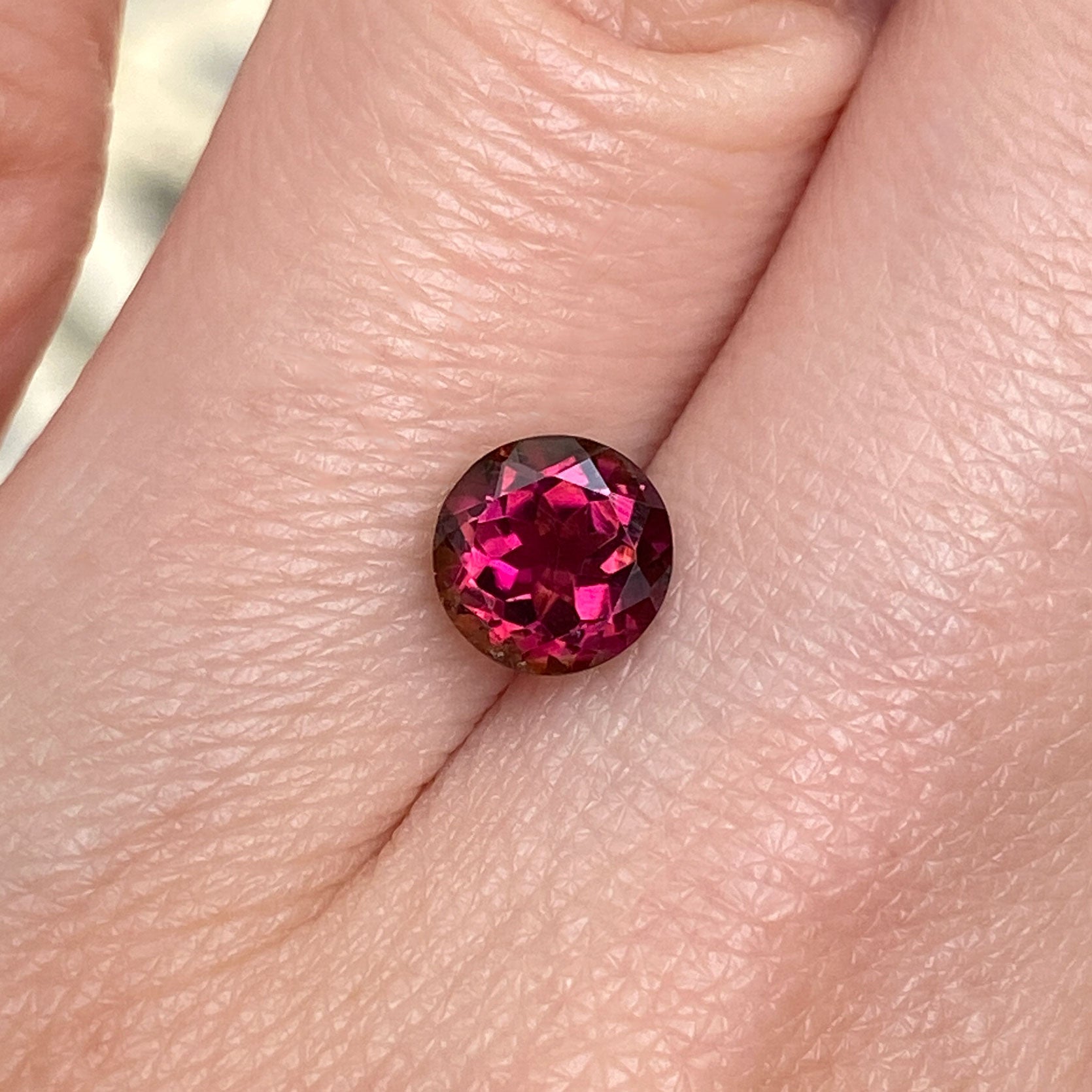 Rich burgundy tourmaline round stone with orange glow