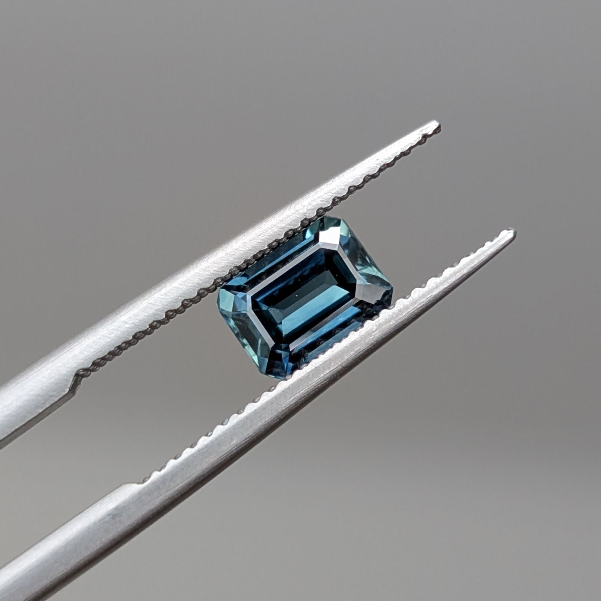 Blue sapphire held between tweezers