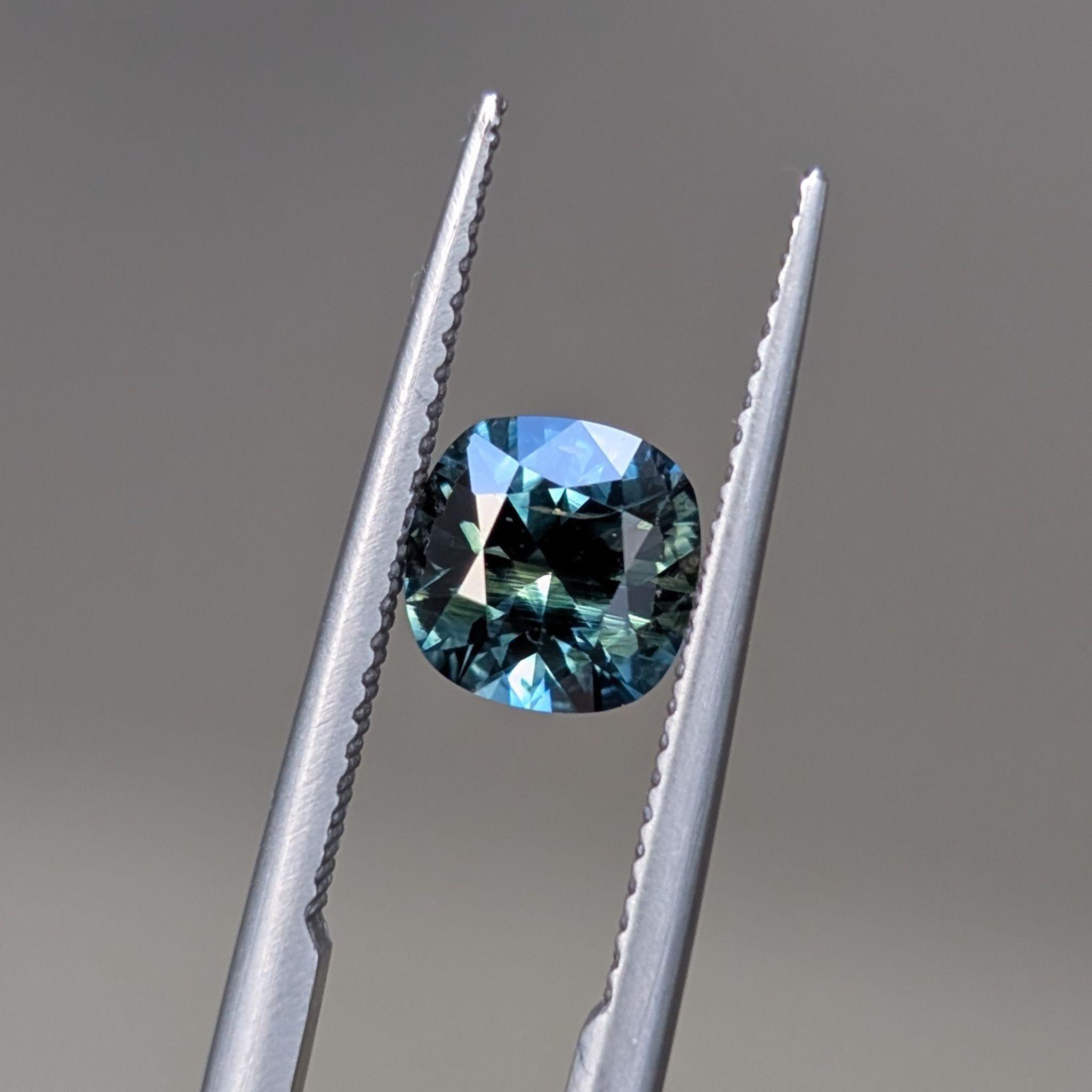 Crisp and symmetrical cushion sapphire with dynamic teal sparkle