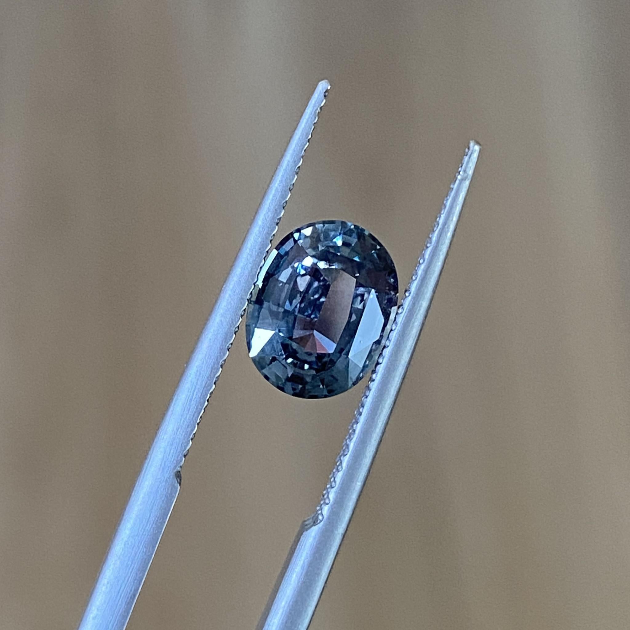 Oval sapphire under soft light, highlighting its dramatic hues and smooth, elegant cut