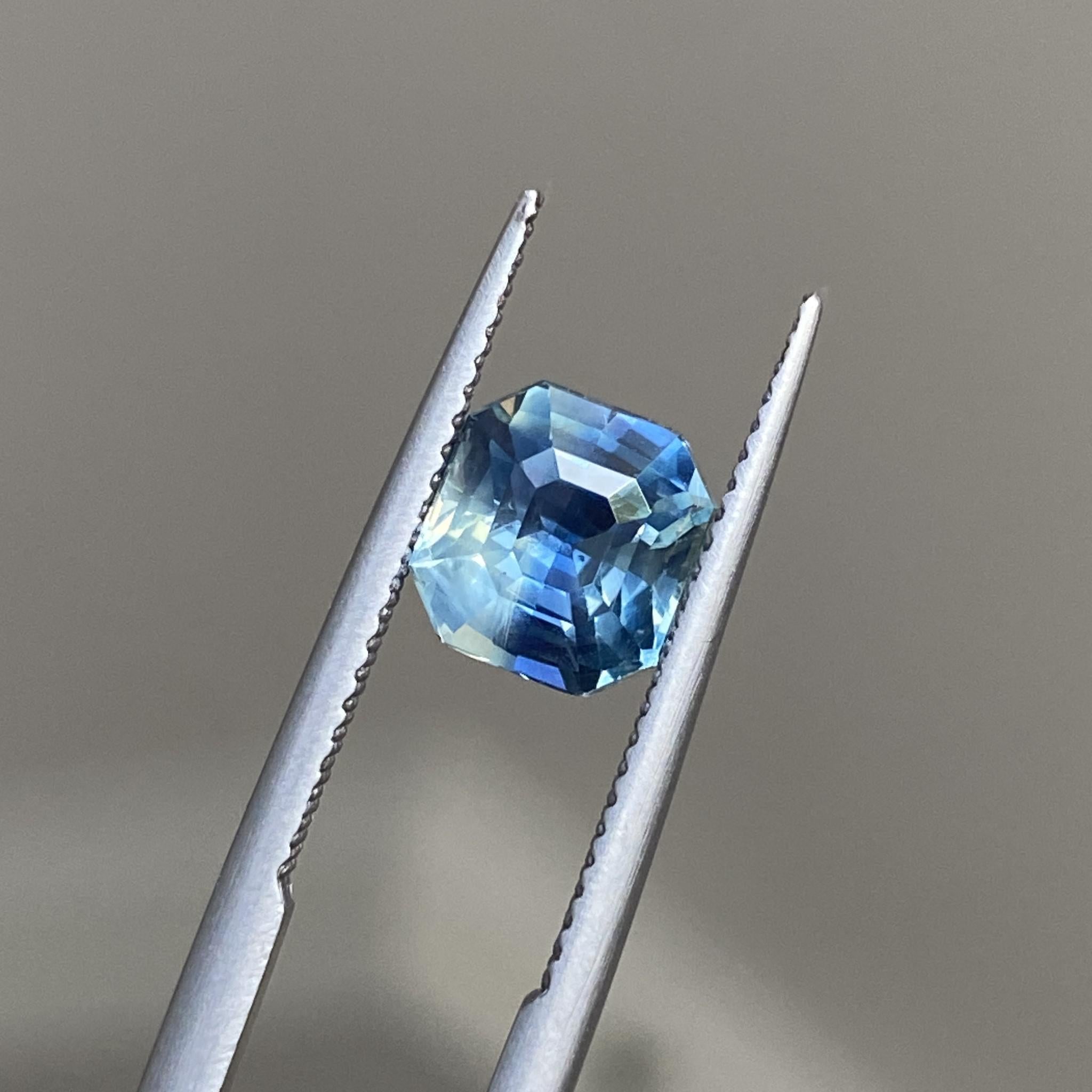 Teal sapphire under soft light, highlighting its bicolour tones and architectural cut.
