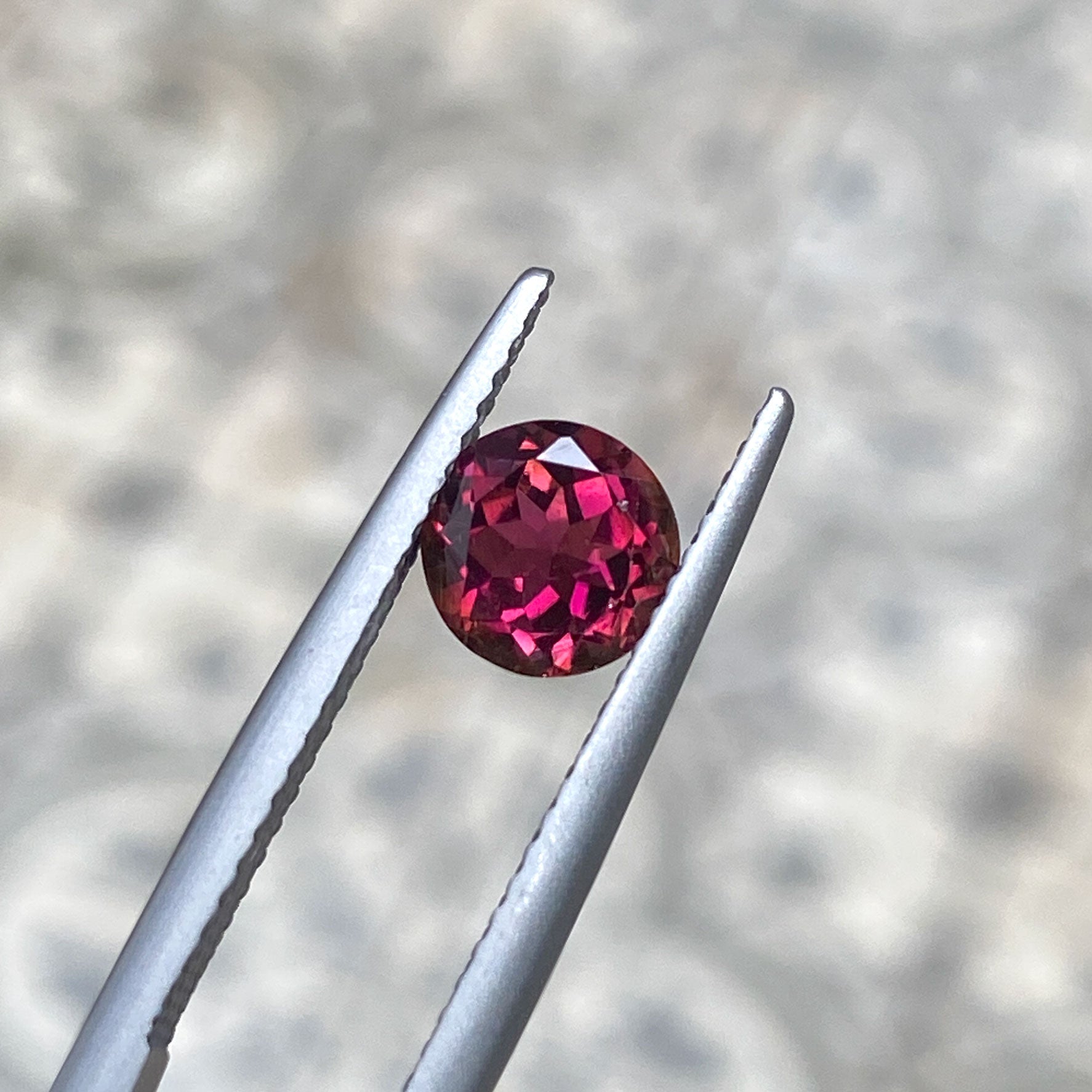 Burgundy round cut tourmaline with warm orange tones
