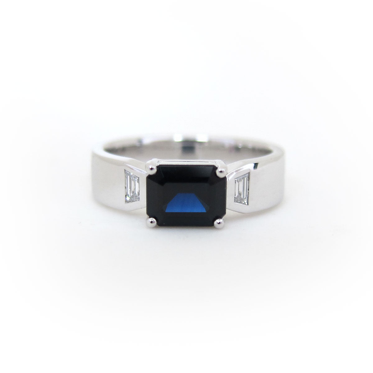 Emerald cut dark blue sapphire ring with trapeze diamonds in white gold