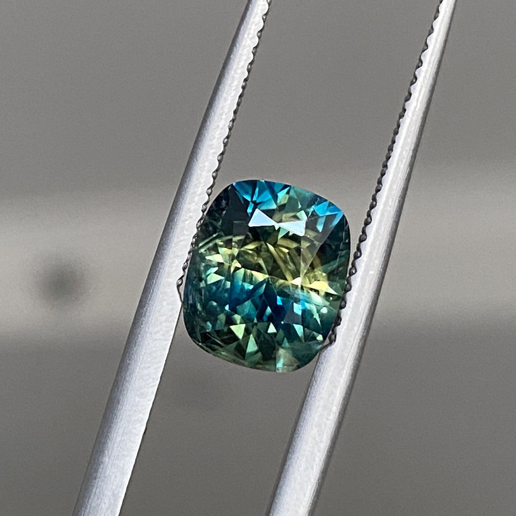 Parti sapphire showing golden-green flashes against deep blue base