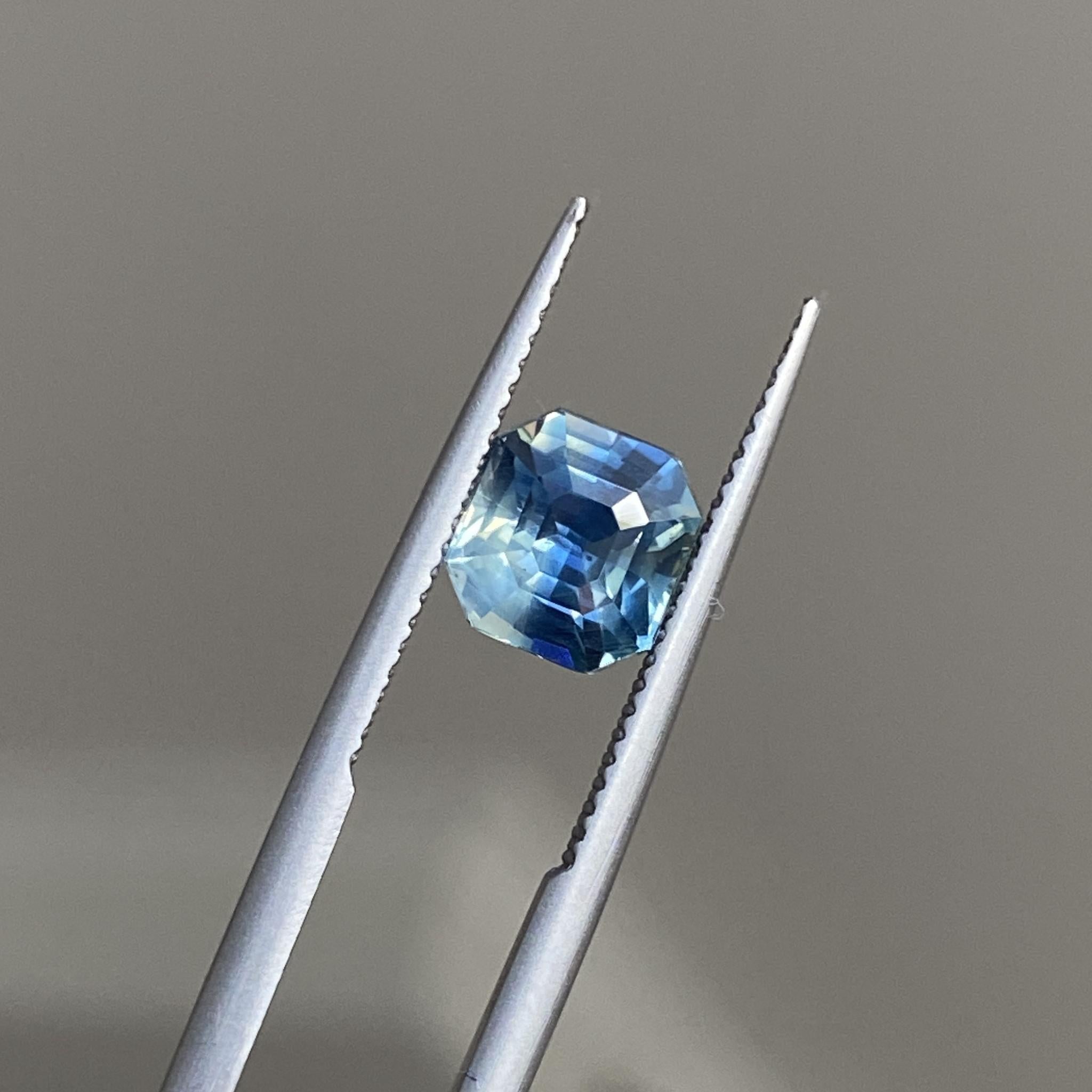 Asscher cut sapphire tilted to reveal its rich teal hues and play of light and shadow