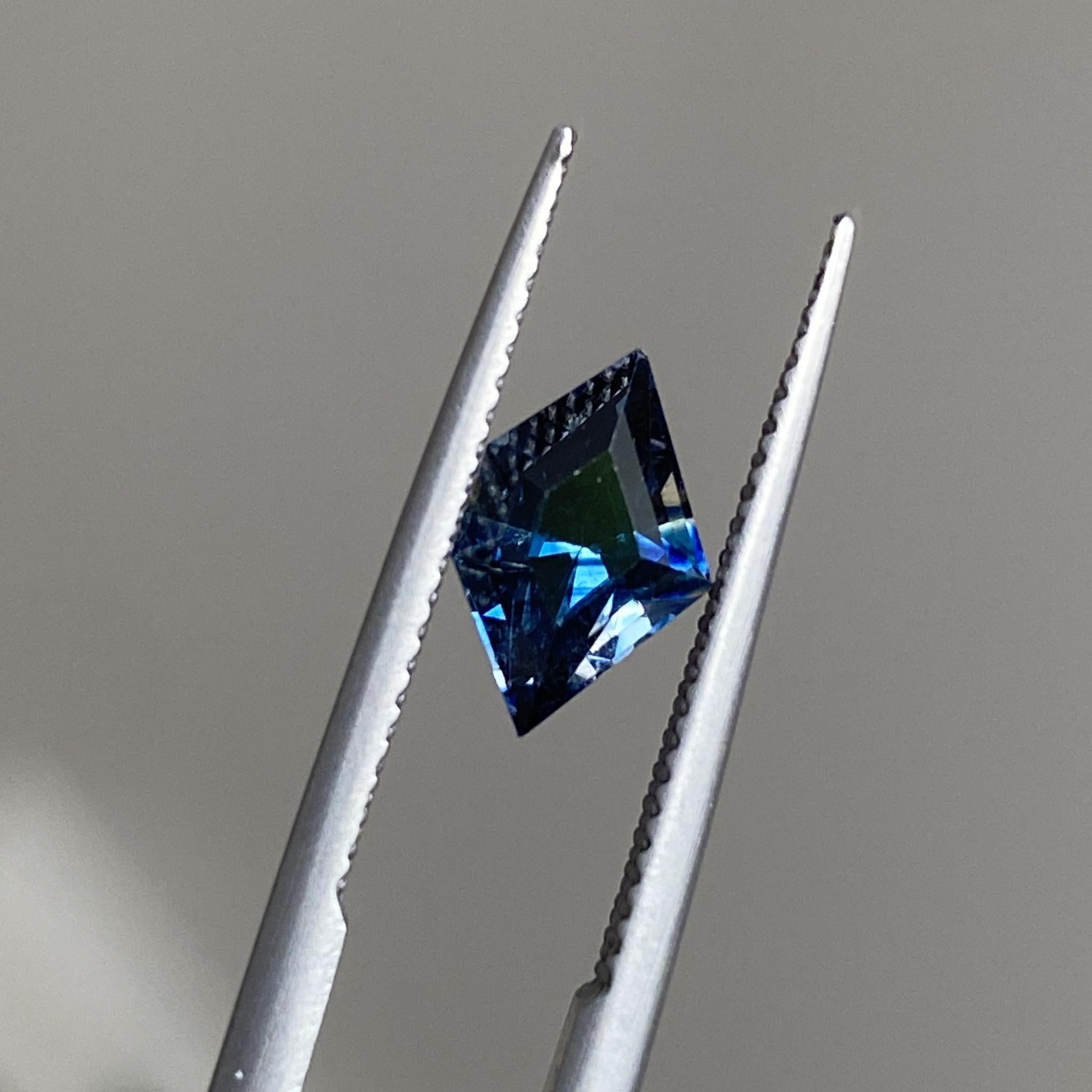 Close-up of the freeform sapphire, emphasizing its rich blue tones and angular geometry.
