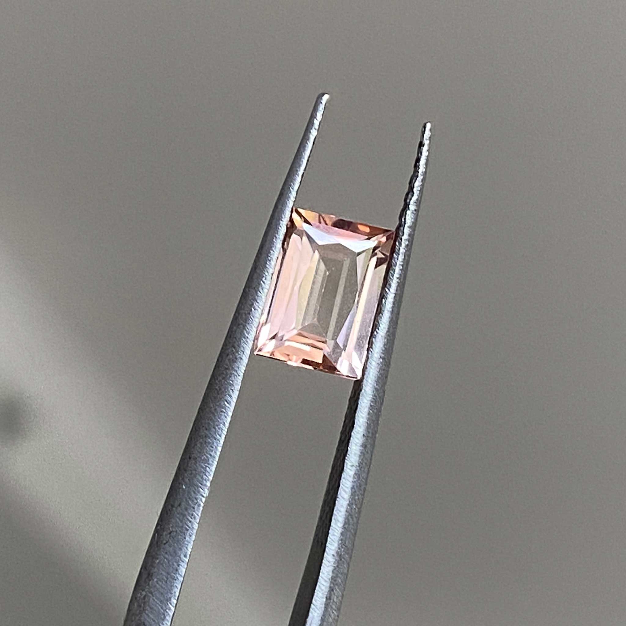 Light dancing across the facets of a peach pink tourmaline